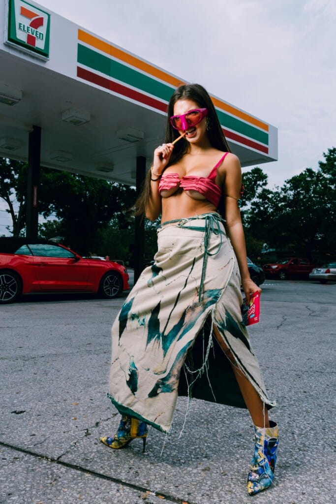 Home 4 A woman in a bikini top and skirt standing in front of a gas station